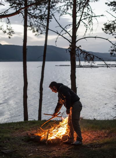 Man lights a fire in the fireplace in nature