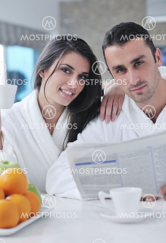Happy couple reading the newspaper in the kitchen at breakfast