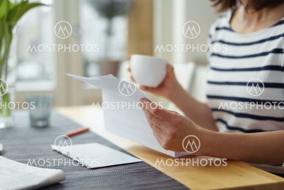 Woman reading a document at the dining table