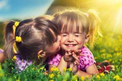 happy girls twin sisters kissing and laughing in the...