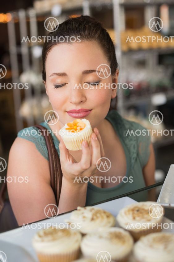Pretty brunette smelling a cupcake