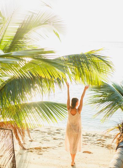 back view of woman standing with hands up between palm...