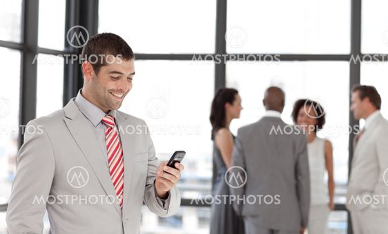 Latin businessman holding a phone at workplace with his colleagues