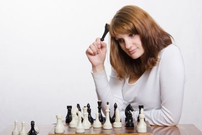 young girl with a figure of Queen, wondered at chess Board