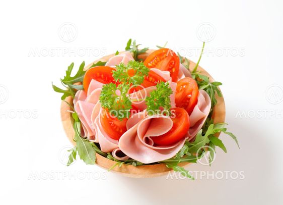 Sliced ham with arugula and tomatoes