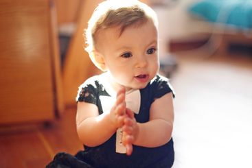 Baby, girl and playing with hands on floor for...