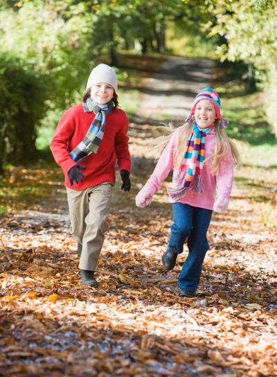 Young boy running along autumn path