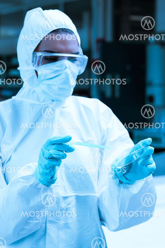 Protected scientist dropping dangerous liquid in a Petri dish