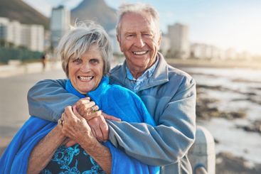 Portrait, seaside and hug with senior couple, smile and...