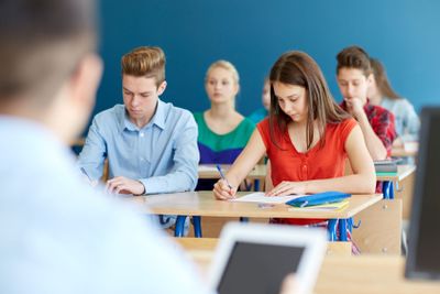 group of students with books writing school test