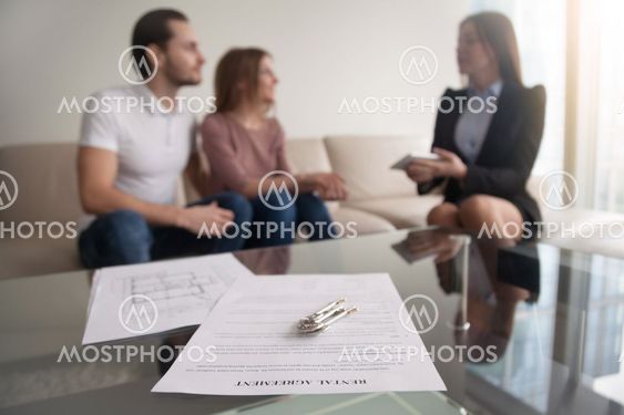 Couple meeting with realtor, focus on rental agreement and keys