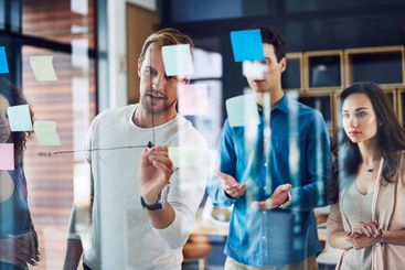 Businessman, writing and planning with team on glass...