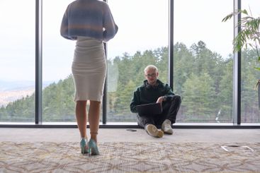A blonde man sitting casually on the floor of a modern...