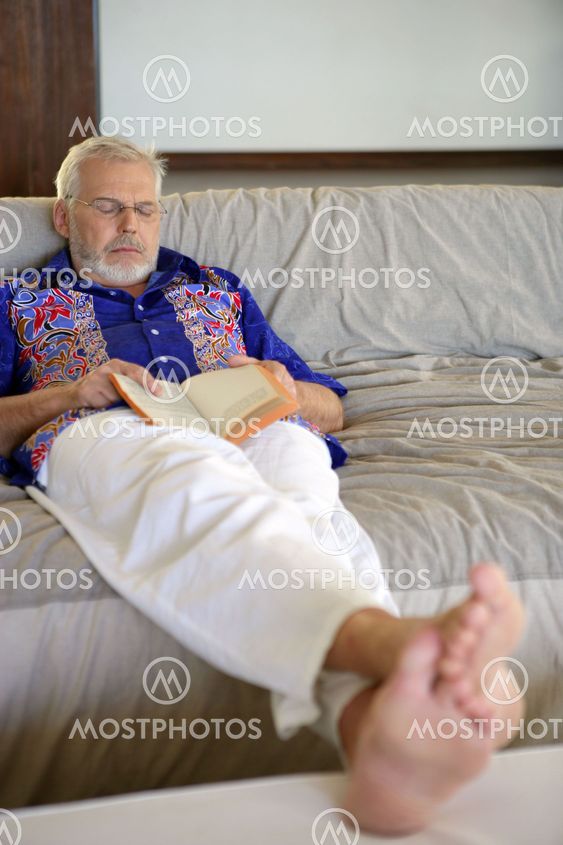 senior holding a book and sleeping on the couch