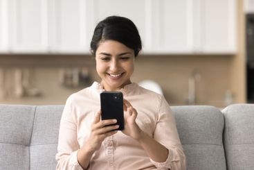 Portrait smiling millennial female sitting on couch...