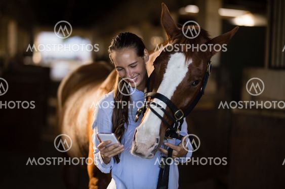 Female vet using mobile phone while standing by horse