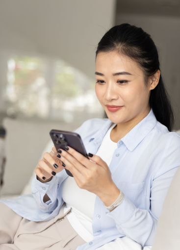 Positive beautiful young Chinese woman typing on cell