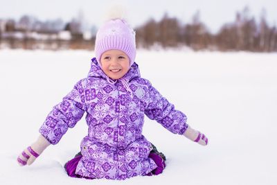 Happy adorable girl having fun on the snow at winter sunny day