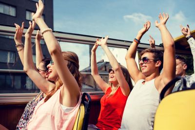 group of smiling friends traveling by tour bus