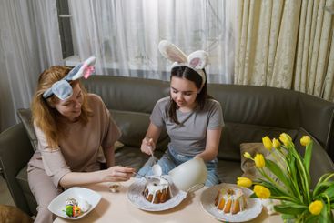 Mother and daughter decorating Easter cakes together.