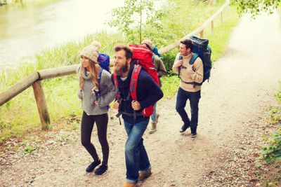 group of smiling friends with backpacks hiking
