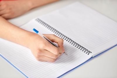 hands of student girl with pen writing to notebook