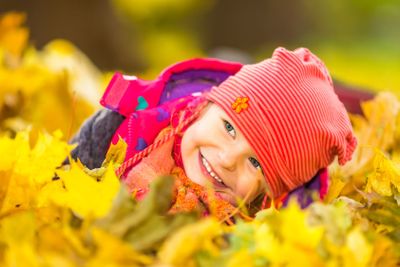 Little girl playing with autumn leaves