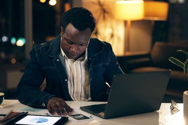 African man, technology and typing at night in office...