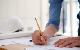 Young architect sketching house plans on a work desk in a...