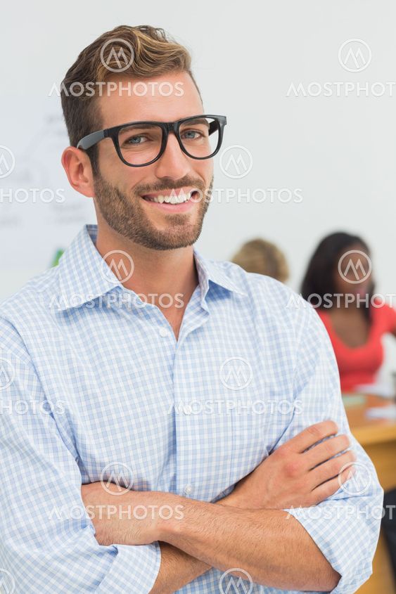 Attractive designer smiling at camera with colleagues behind him
