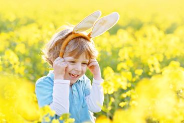 little kid boy having fun with traditional Easter egg hunt
