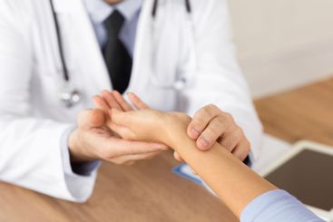 Doctor checking measuring pressure on patient's hand pulse
