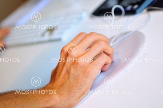 lose-up of male hand on mouse while working on laptop