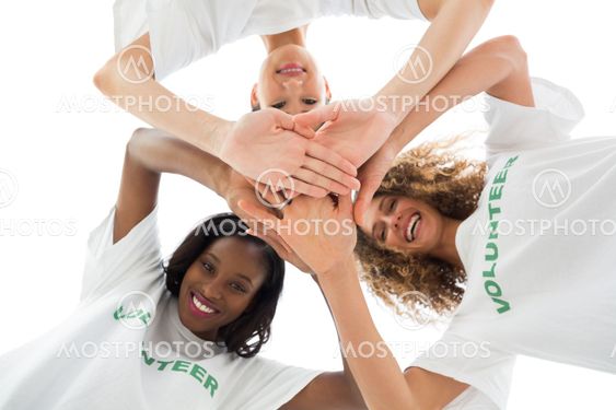 Happy volunteers putting hands together and looking down at camera