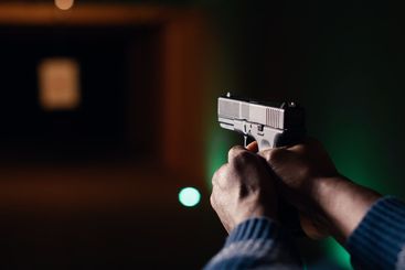 Man holding pistol at indoor shooting range, close up