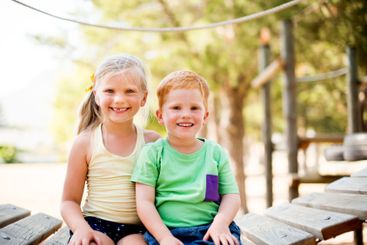 Happy, portrait and kids sitting in park for bonding,...