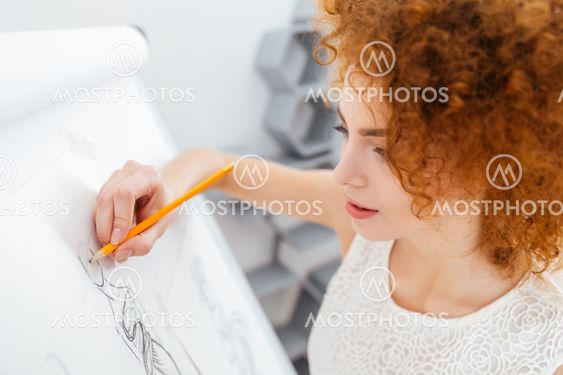 Beautiful woman fashion designer making sketches on...