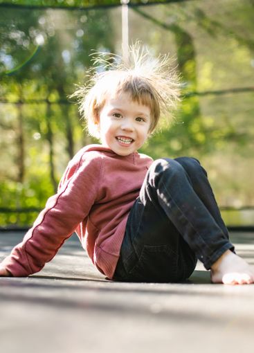 Little boy jumping on a trampoline in a backyard on warm...