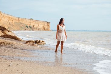 a woman in white clothes stands on the seashore