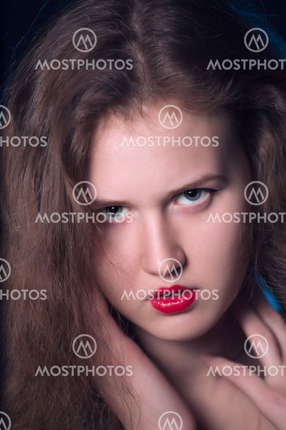 Portrait of a beautiful teen girl with long curly hairs and red lips