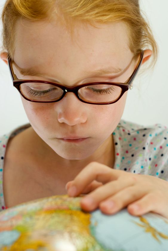 Smart Red Head Looking at Globe with Glasses