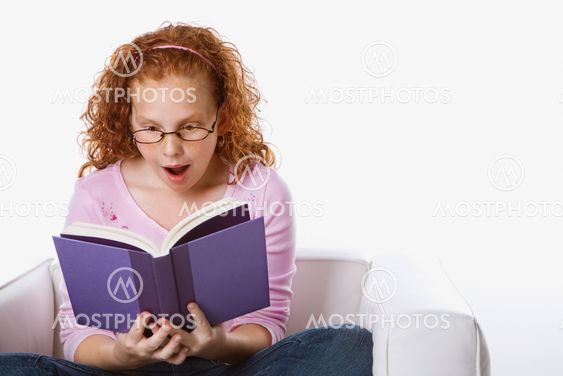 Girl reading book looking surprised.