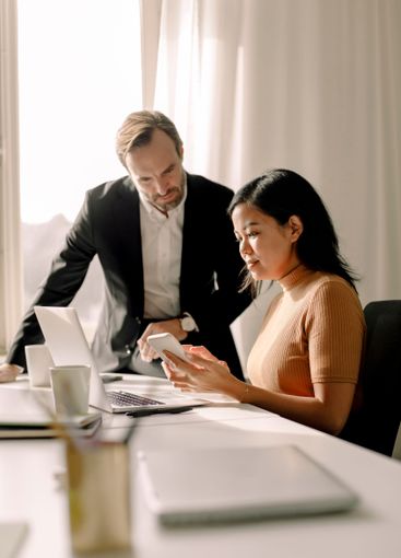 Businesswoman sharing smart phone with businessman in...