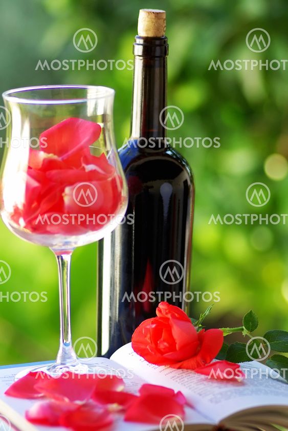 Petals of red rose in glass of wine.