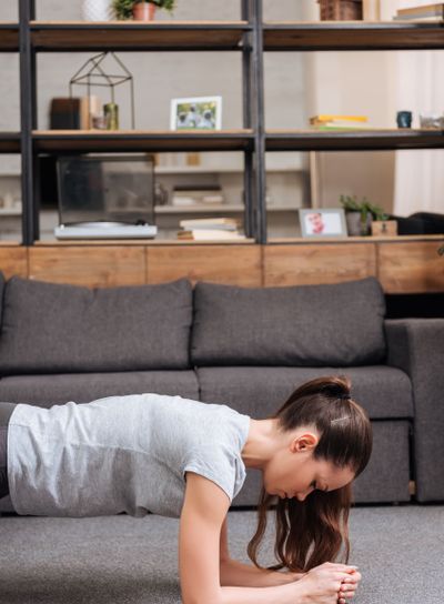 focused sportswoman doing plank exercise at home in...