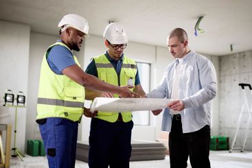Three professionals inspecting house construction with...