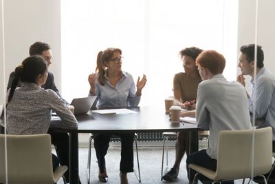 Middle-aged businesswoman speaking at diverse group...