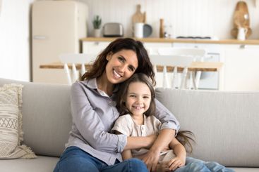 Beautiful mommy little daughter cuddling on couch...