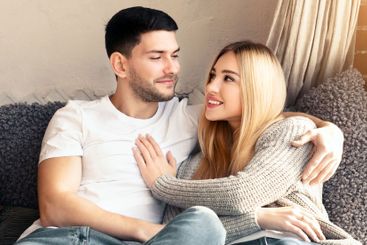 Affectionate boyfriend and girlfriend cuddling on sofa...