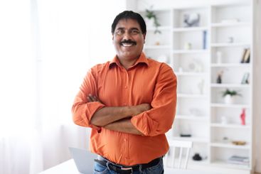Handsome cheerful mature indian man posing at home office